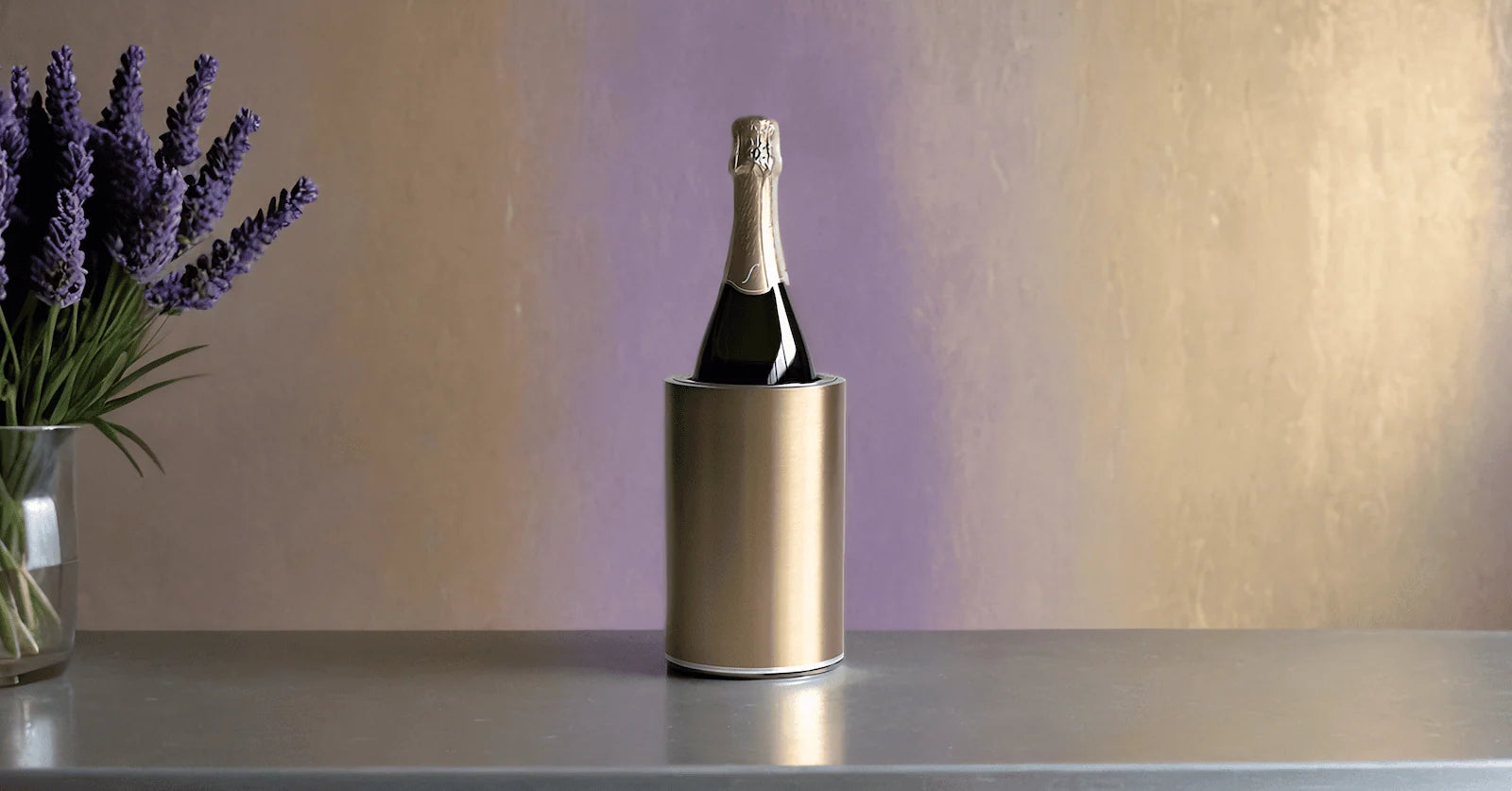 Coolenator gold design wine cooler with a bottle of wine on a grey table with lavender in a vase next to it.