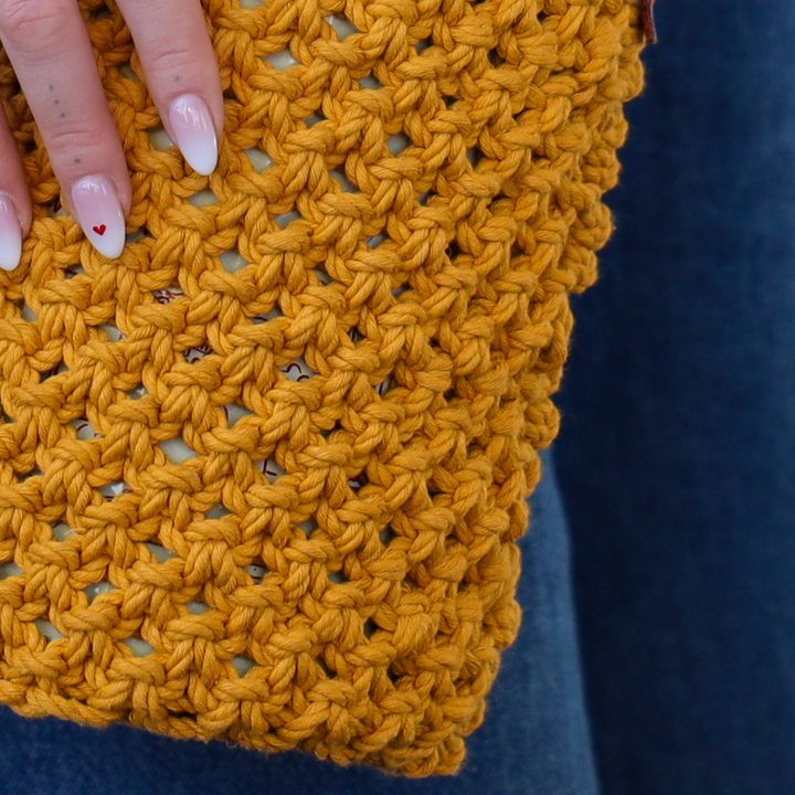 A close up of the yellow crochet bag with the coolenator in it.