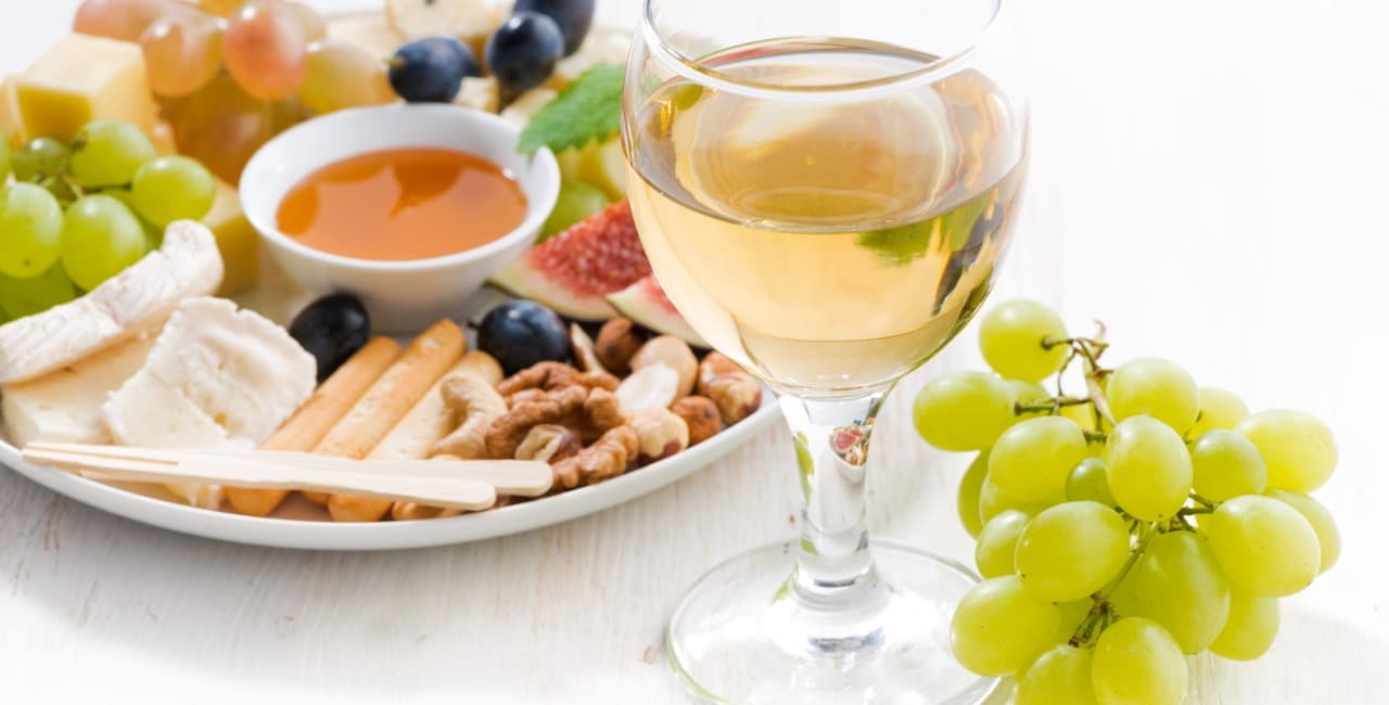 snacks on a plate with a glass of cold white wine