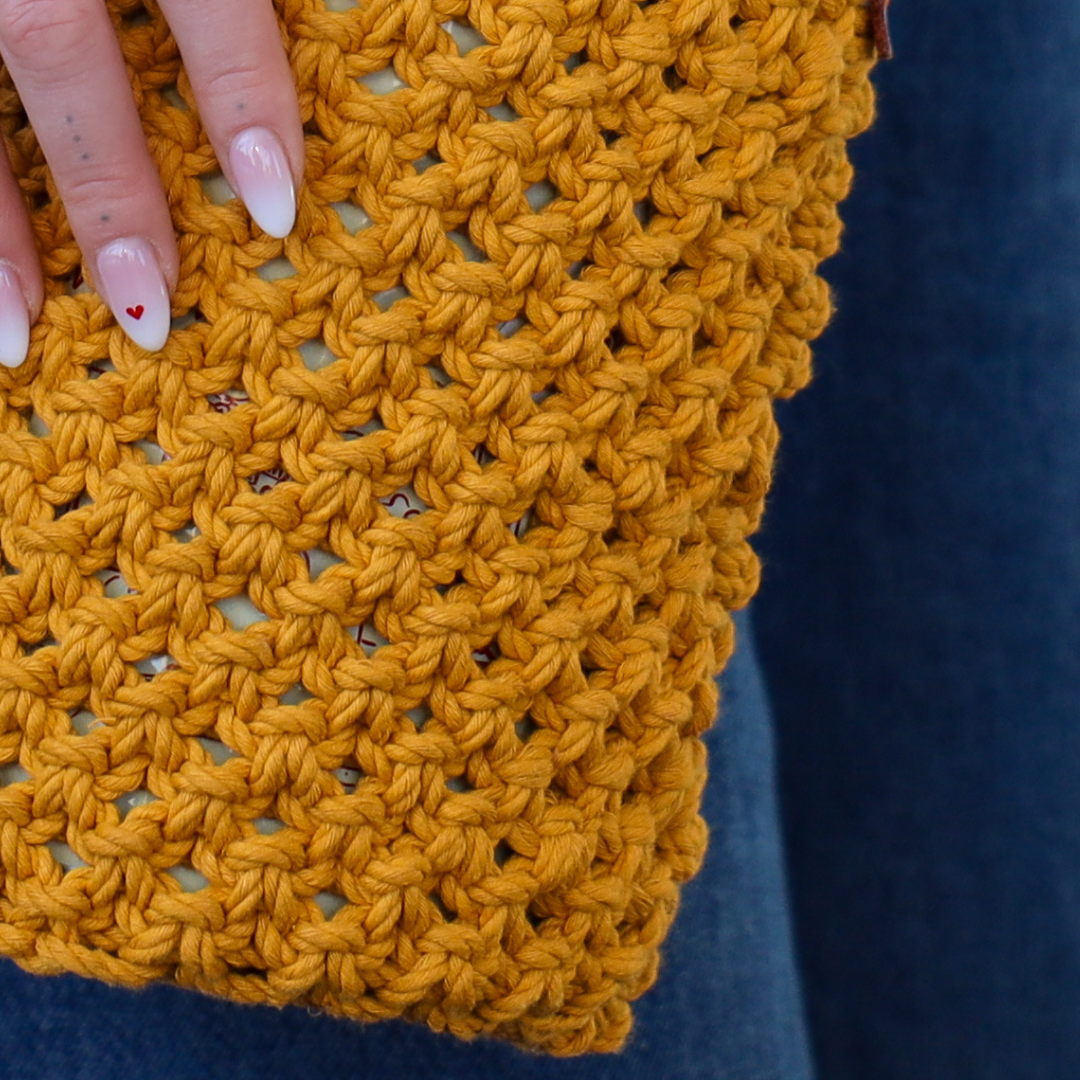 A close up of the yellow crochet bag with the coolenator in it. 